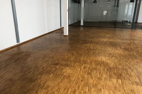 Empty office floor with industrial parquet, a steel column and a floor-to-ceiling glass partition