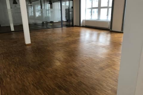 Empty office floor with industrial parquet, glass partitions and a tall window front