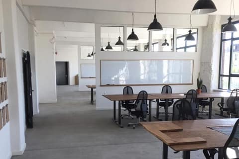 Open-plan office with timber desks and industrial pendant lights after fit-out