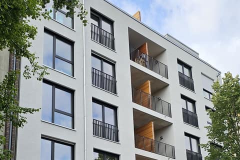 Street façade of a completed apartment building with loggias and timber cladding